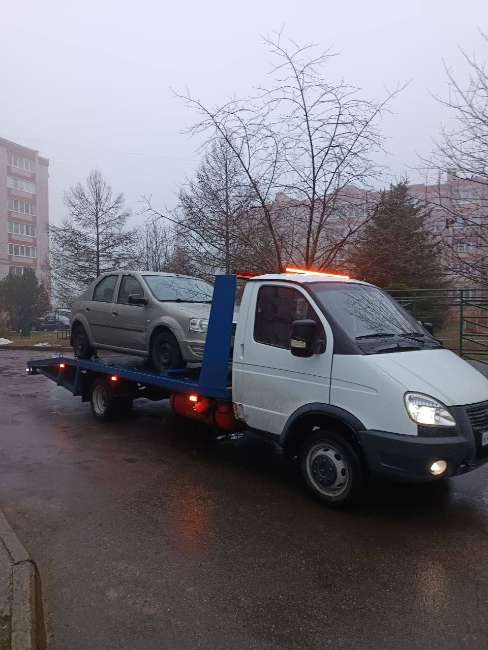 Эвакуатор забирает легковой автомобиль во дворе в Великом Новгороде
